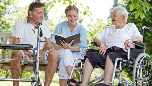 In Deutschland engagieren sich rund 31 Millionen Menschen ehrenamtlich.  Junge Frau liest zwei älteren Menschen aus einem Buch vor
