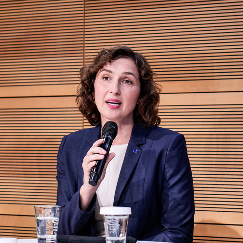 Eine Frau sitzt auf einer Bühne und spricht in ein Mikrofon