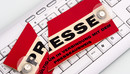 Auf einer Computertastatur liegt ein in Zwei geteiltes Schild mit der Aufschrift Presse