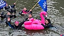 Eine Gruppe Menschen schwimmt in Neoprenanzügen in einem Fluss