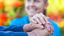 Junge Frau legt Hand auf die Hand eines Senioren