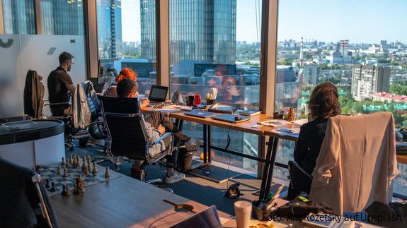 Menschen an einem modernen Arbeitsplatz vor Laptops