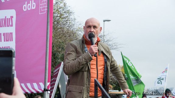 Einkommensrunde Aktion Kiel  Ein Mann steht vor einer Gruppe Menschen und spricht in ein Mikrofon