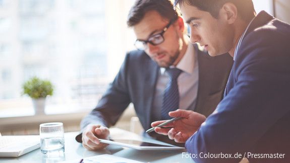 Digitalisierung Zwei Männer im Büro sehen gemeinsam auf Tablet und besprechen sich