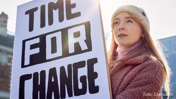 Eine junge Frau hält bei einer Demonstration ein Plakat mit der Aufschrift "Time for Change" hoch.