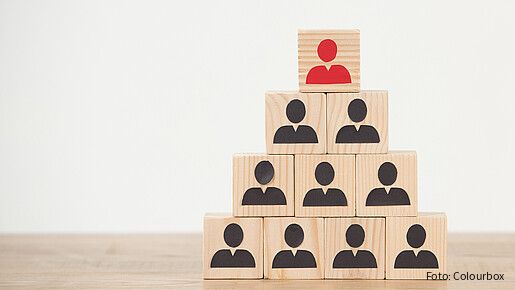 Das Foto zeigt Würfel, die als Pyramide gestapelt sind. Auf den Würfeln jeweils Figuren, die oberste ist rot. 