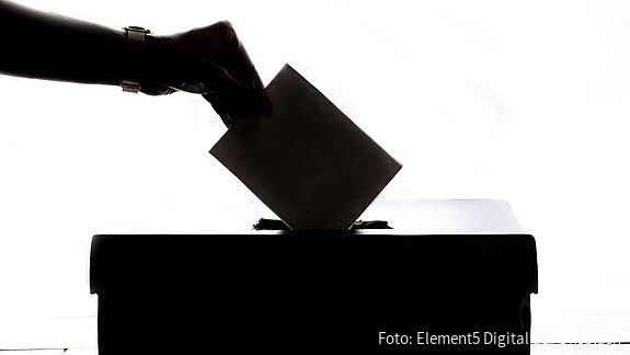 Ein Wahlschein wird in die Wahlurne eingeworfen