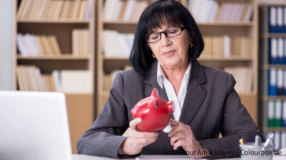 Seniorin mit Sparschwein