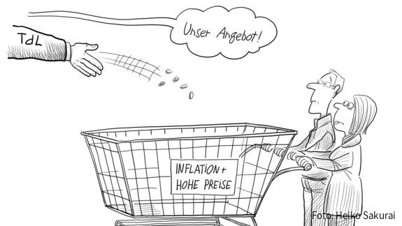 Eine Hand mit der Aufschrift "TdL" wirft ein paar Münzen in einen Einkaufswagen mit der Aufschrift "Inflation & hohe Preise"