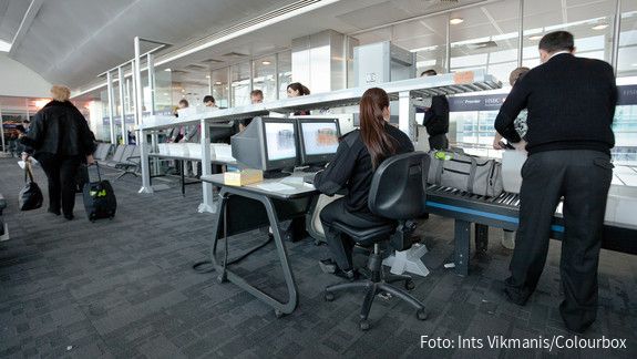 Das Bild zeigt Mitarbeitende des Sicherheitspersonals bei der Sicherheitskontrolle am Flughafen.