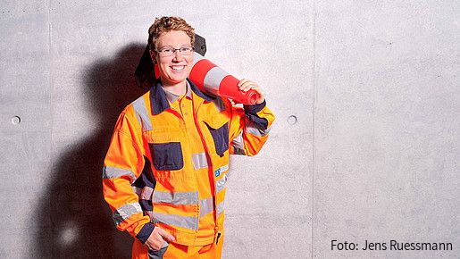Foto zum Thema "Ausbildung zum Straßenwärter": Zu sehen ist Sandy, die Einblicke in den Job gibt. Sie trägt orangefarbige Sicherheitskleidung. 