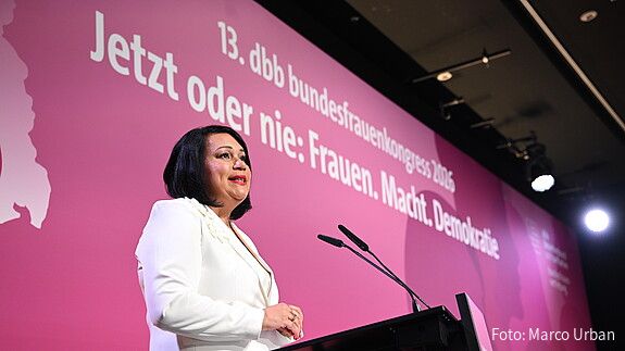 Eine Frau steht auf einer Bühne und spricht in ein Rednerpult