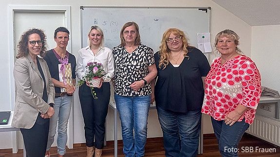 Eine Gruppe Frauen steht vor einem Whiteboard und blicken in Richtung Kamera