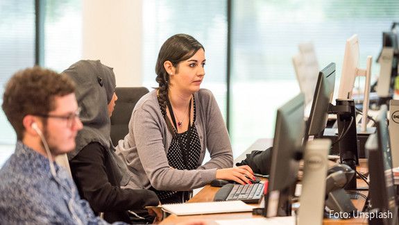 Büro Blick in ein Büro auf einen jungen Mann und zwei Frauen, eine von ihnen trägt ein Kopftuch. Alle schauen auf ihre Computer-Bildschirme