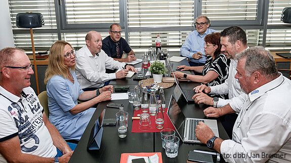 Eine Gruppe Menschen sitzt um einen Besprechungstisch und diskutiert