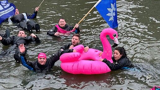 Eine Gruppe Menschen schwimmt in Neoprenanzügen in einem Fluss