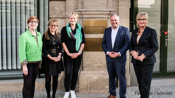 Fünf Menschen stehen vor einem Gebäudeeingang